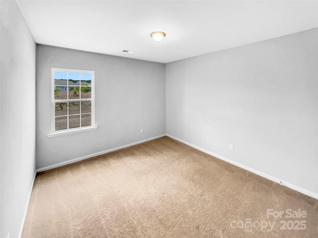 empty room featuring carpet flooring, visible vents, and baseboards