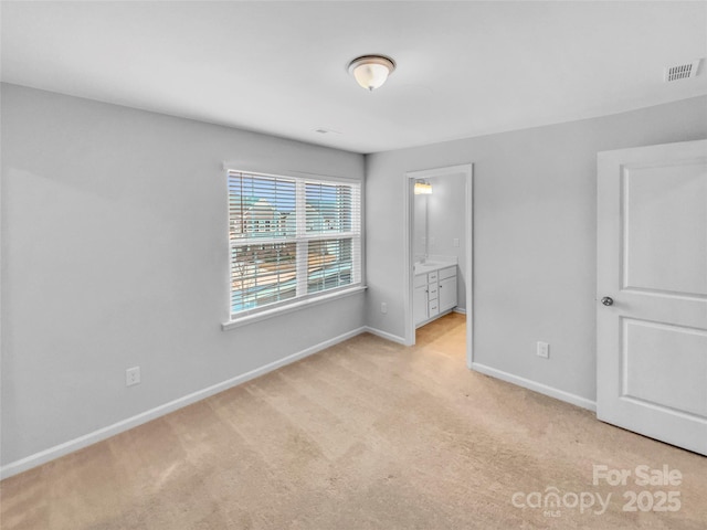 unfurnished bedroom featuring visible vents, light colored carpet, baseboards, and connected bathroom