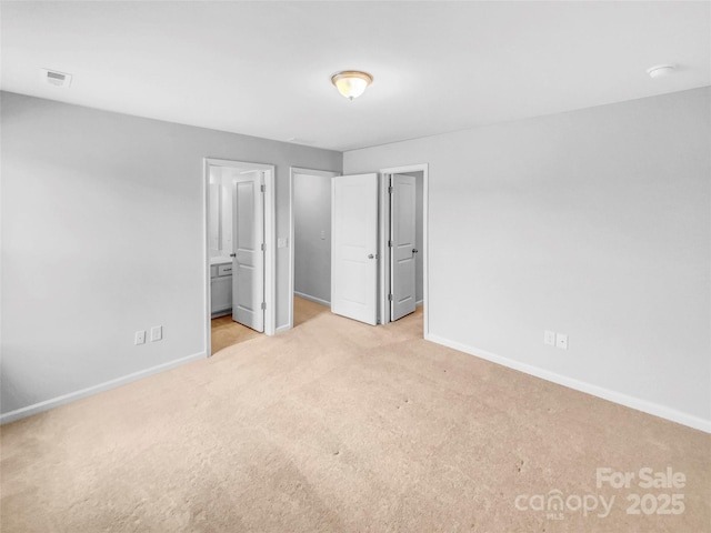 unfurnished bedroom featuring visible vents, baseboards, ensuite bathroom, and carpet