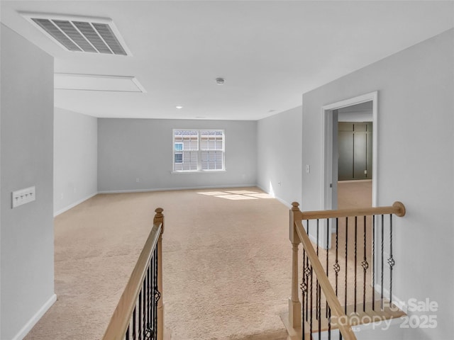 carpeted empty room featuring visible vents, baseboards, and attic access