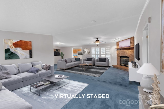 living area with a brick fireplace, a textured ceiling, and a ceiling fan