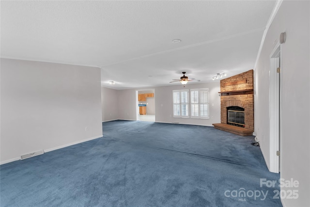 unfurnished living room featuring visible vents, baseboards, ceiling fan, dark carpet, and a fireplace