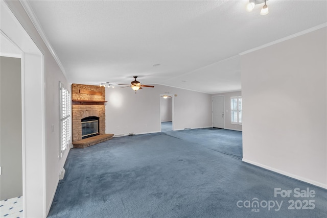 unfurnished living room featuring carpet floors, lofted ceiling, a fireplace, ceiling fan, and crown molding