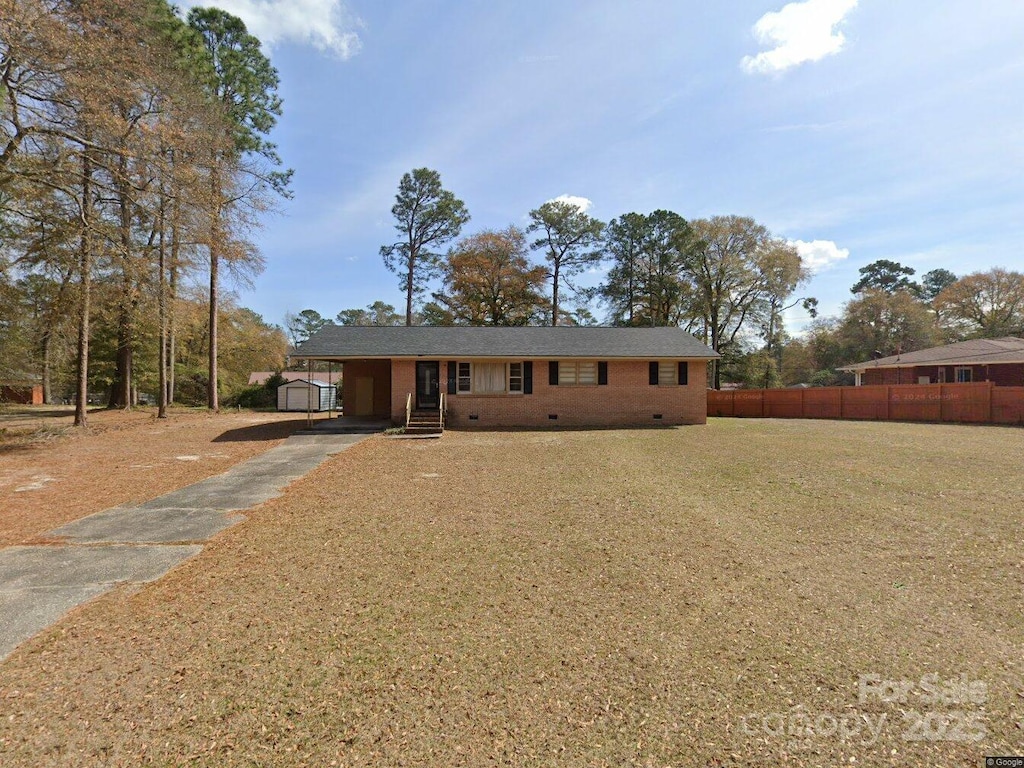ranch-style home with an attached carport, fence, a front yard, crawl space, and brick siding