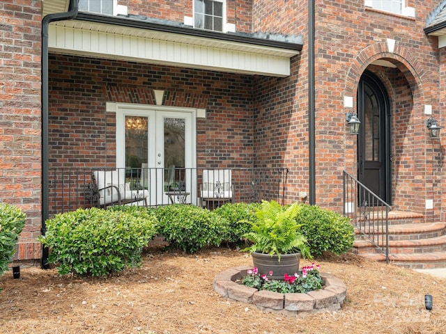 view of exterior entry featuring brick siding and french doors