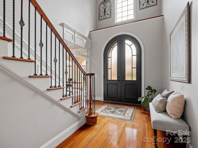 foyer featuring stairway, arched walkways, wood finished floors, and a towering ceiling