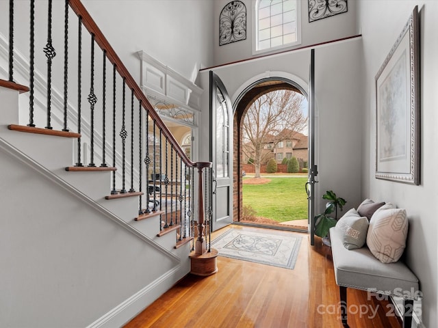 entrance foyer with stairway, baseboards, a high ceiling, and wood finished floors