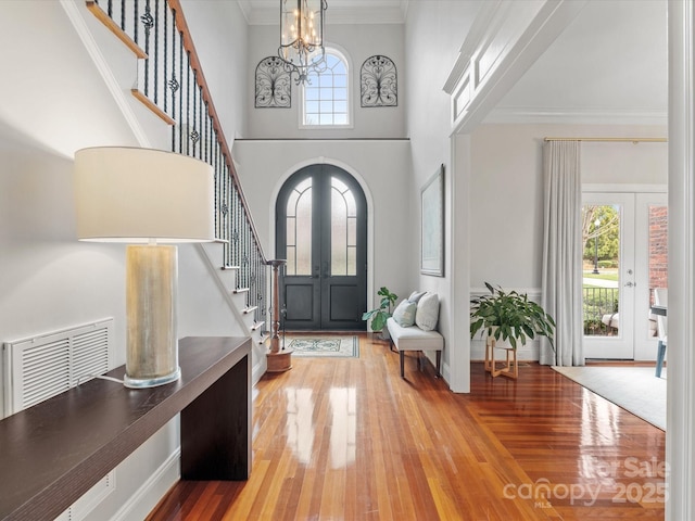 foyer entrance with french doors, visible vents, crown molding, and stairway