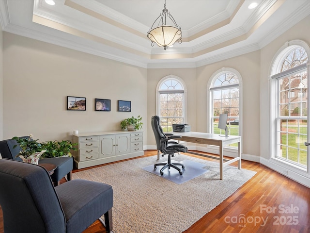 office area with light wood-type flooring, a notable chandelier, baseboards, crown molding, and a raised ceiling