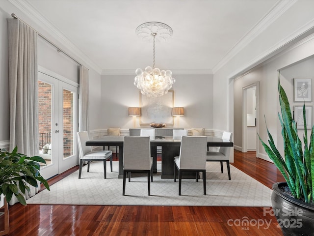 dining room with wood finished floors, french doors, an inviting chandelier, crown molding, and baseboards