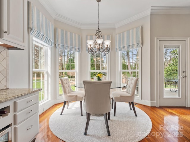 dining space with a chandelier, plenty of natural light, light wood-style floors, and ornamental molding