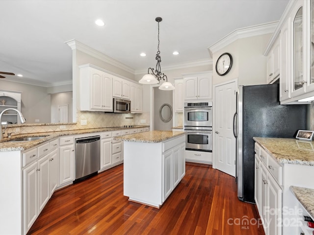 kitchen featuring a kitchen island, a sink, glass insert cabinets, appliances with stainless steel finishes, and white cabinetry