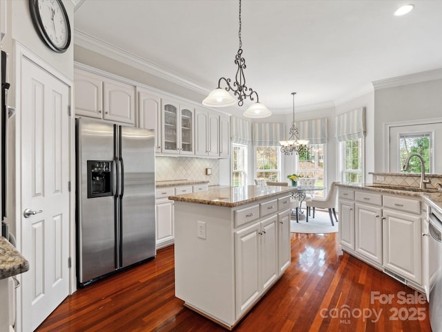 kitchen featuring a kitchen island, white cabinetry, stainless steel appliances, and a sink