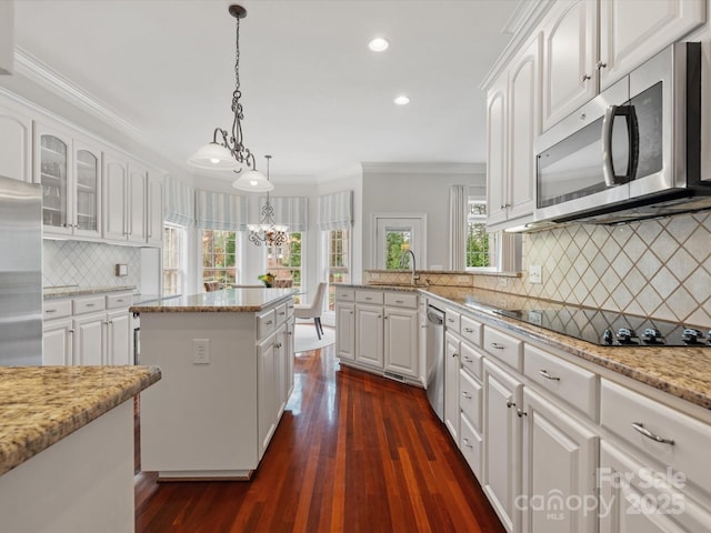 kitchen with white cabinetry, stainless steel appliances, crown molding, and a sink