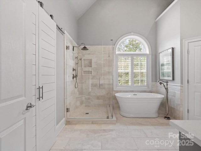 bathroom featuring a wainscoted wall, a stall shower, a freestanding bath, vaulted ceiling, and tile walls