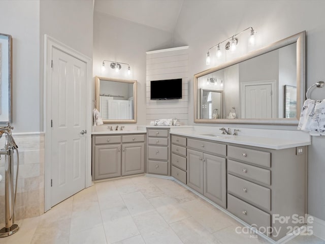 full bathroom featuring vanity, lofted ceiling, and tile walls