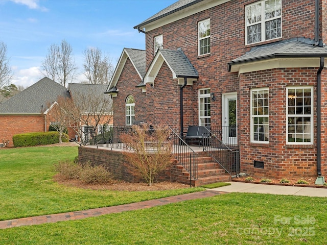 back of house with a yard, brick siding, and a shingled roof