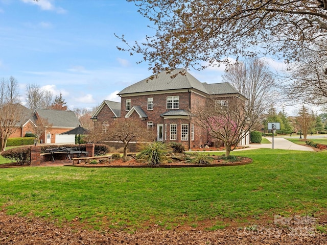 back of property with brick siding, a lawn, driveway, and roof with shingles