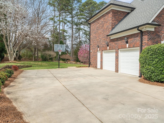 view of property exterior with a yard, brick siding, driveway, and a shingled roof