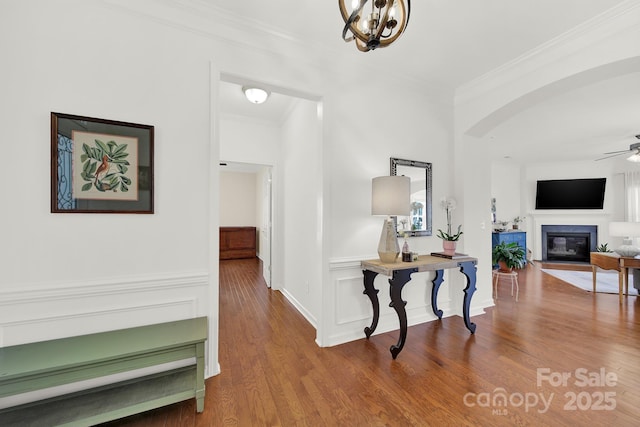 hall featuring crown molding, wood finished floors, and arched walkways