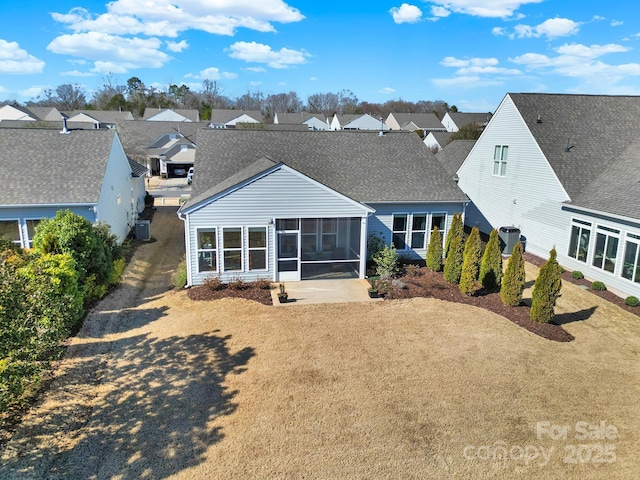 back of house with a residential view, a shingled roof, and a sunroom