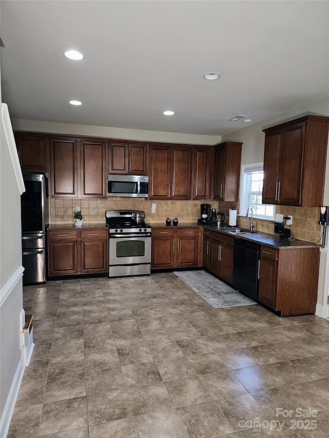 3500 Exbury Gardens Dr, Waxhaw, NC 28173 - kitchen featuring backsplash, a sink, dark countertops, dark brown cabinets, and appliances with stainless steel finishes