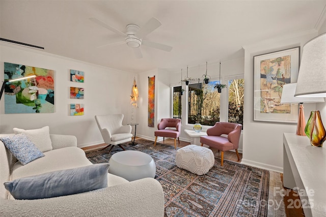 living room with baseboards, crown molding, ceiling fan, and wood finished floors