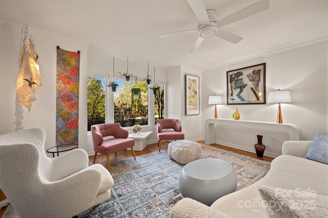 living area with ornamental molding, baseboards, ceiling fan, and wood finished floors