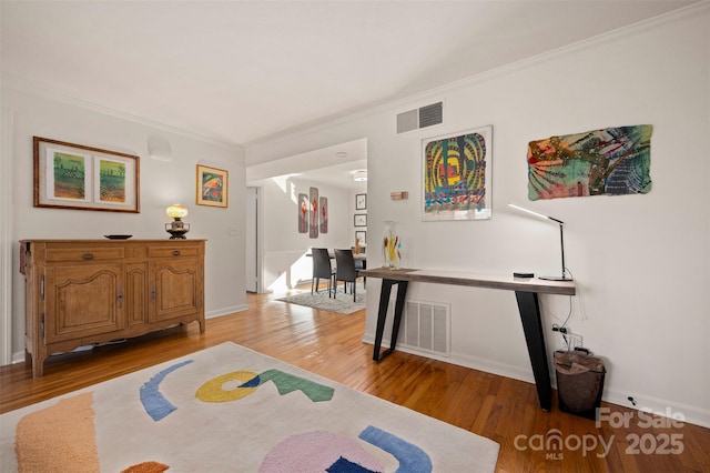 interior space with crown molding, baseboards, visible vents, and light wood-type flooring