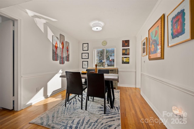 dining room featuring light wood finished floors, baseboards, and ornamental molding