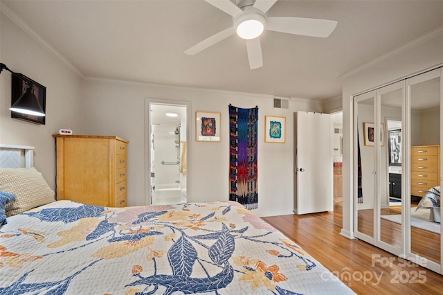 bedroom featuring a ceiling fan, wood finished floors, visible vents, ensuite bath, and crown molding