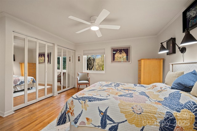 bedroom featuring ceiling fan, wood finished floors, two closets, and ornamental molding