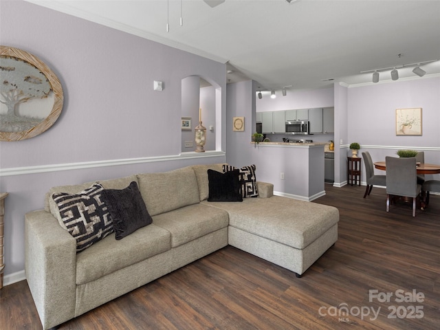 living area with crown molding, baseboards, dark wood-type flooring, and ceiling fan