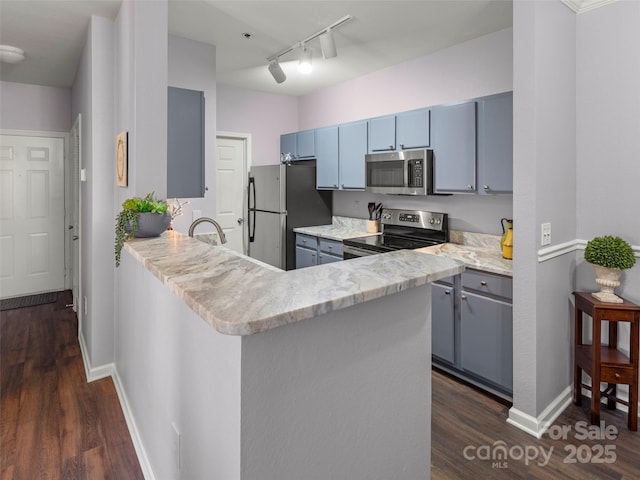 kitchen featuring dark wood-type flooring, gray cabinetry, blue cabinetry, stainless steel appliances, and a peninsula