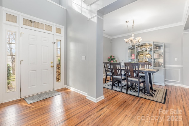 foyer featuring baseboards, an inviting chandelier, ornamental molding, and hardwood / wood-style flooring