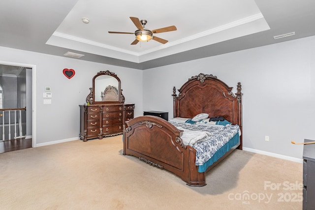 bedroom featuring light carpet, visible vents, baseboards, and a tray ceiling