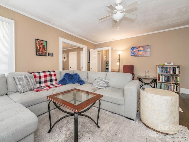 living room with ceiling fan, wood finished floors, baseboards, and ornamental molding