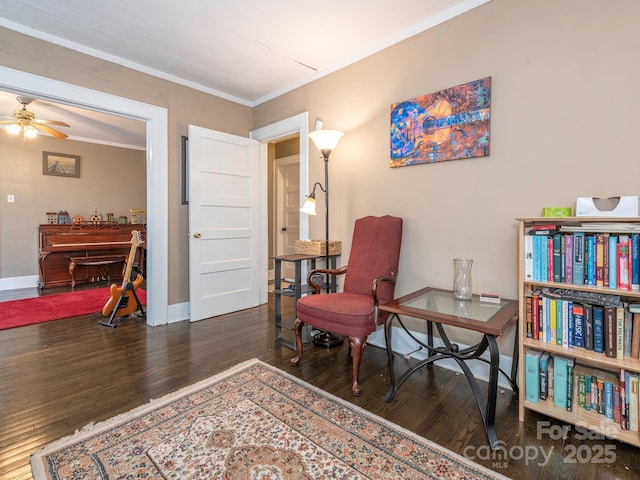 living area featuring baseboards, wood finished floors, ornamental molding, and a ceiling fan