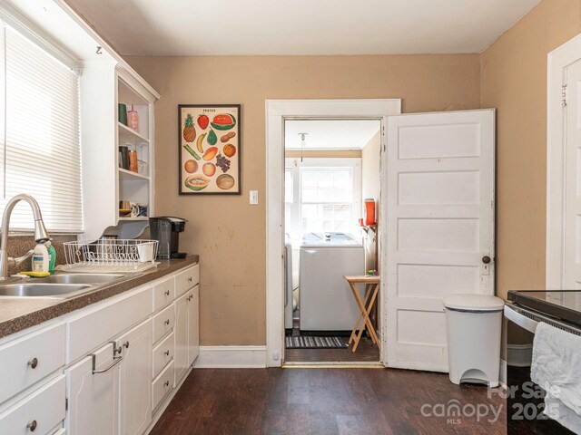 kitchen with independent washer and dryer, a sink, open shelves, dark wood-style floors, and white cabinets