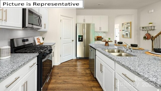 kitchen featuring dark wood-type flooring, a sink, appliances with stainless steel finishes, white cabinets, and light stone countertops