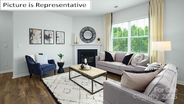 living room with a glass covered fireplace, visible vents, baseboards, and dark wood finished floors