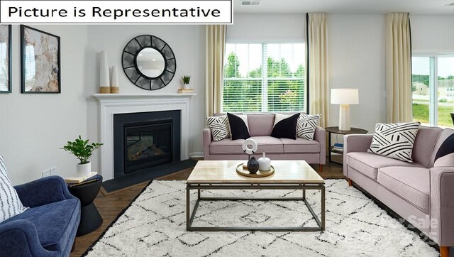 living room with a glass covered fireplace, wood finished floors, and visible vents