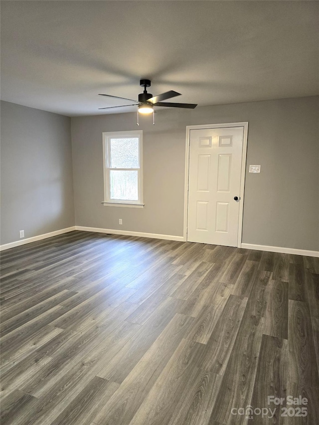 empty room with baseboards, dark wood-style flooring, and ceiling fan