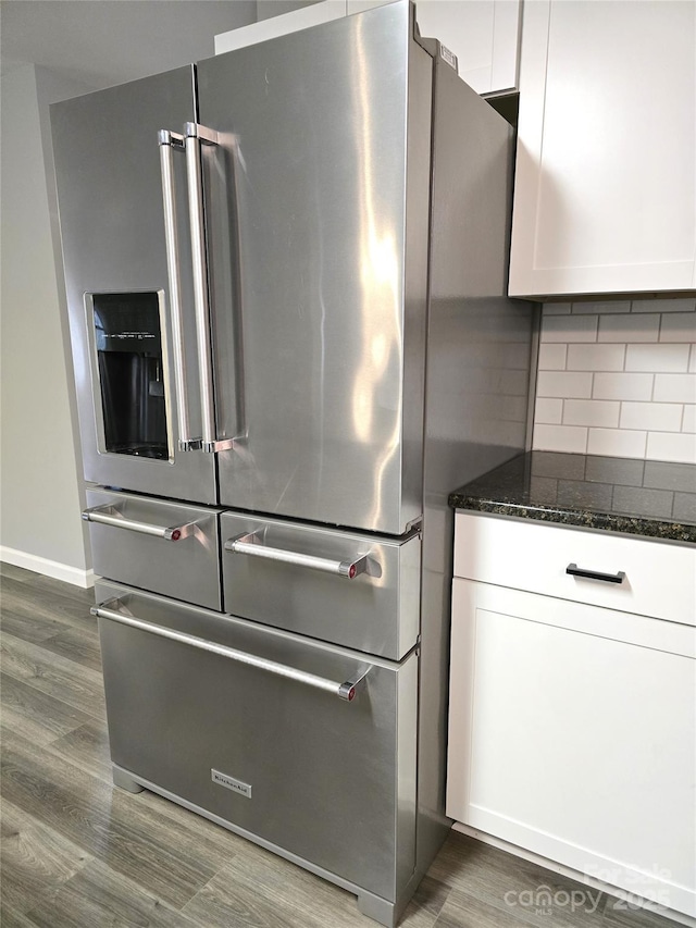 room details with dark stone countertops, tasteful backsplash, dark wood finished floors, white cabinetry, and stainless steel fridge