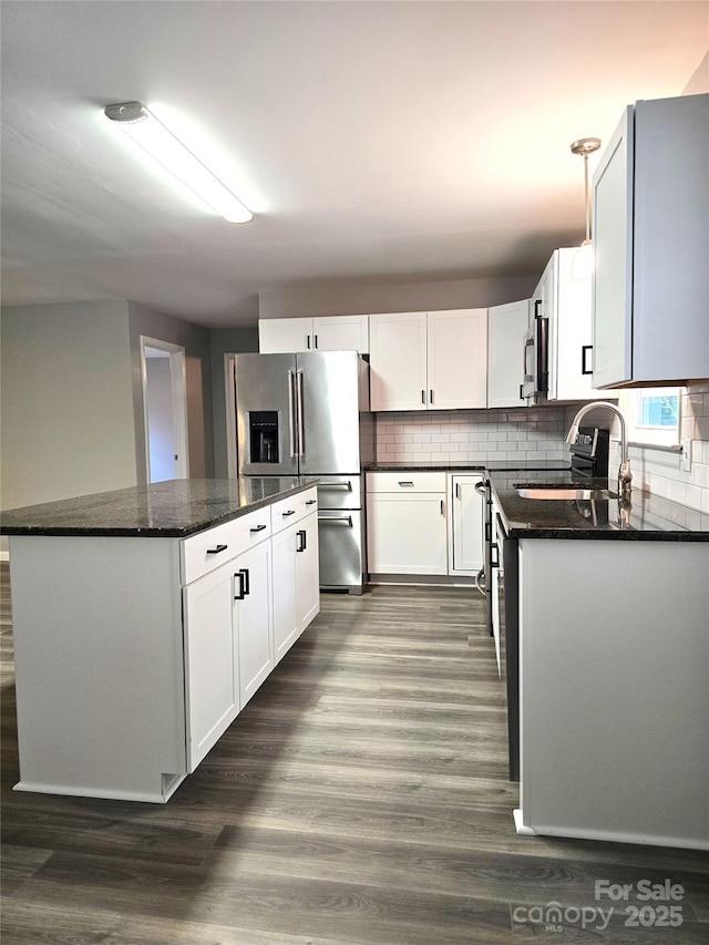 kitchen with tasteful backsplash, a center island, dark wood finished floors, appliances with stainless steel finishes, and a sink