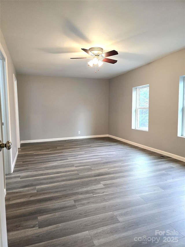 empty room with dark wood-style floors, a ceiling fan, and baseboards