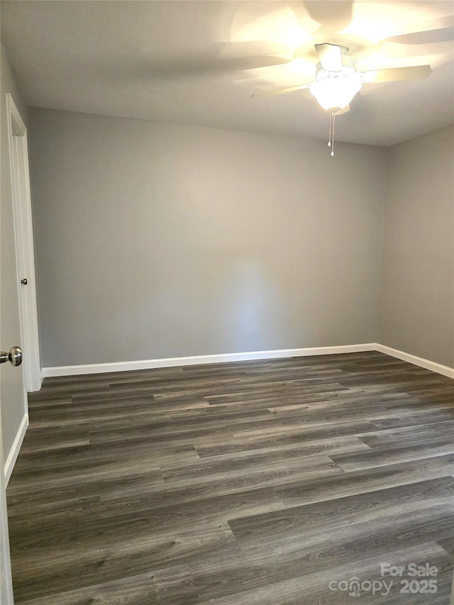 empty room featuring baseboards, dark wood-style flooring, and ceiling fan