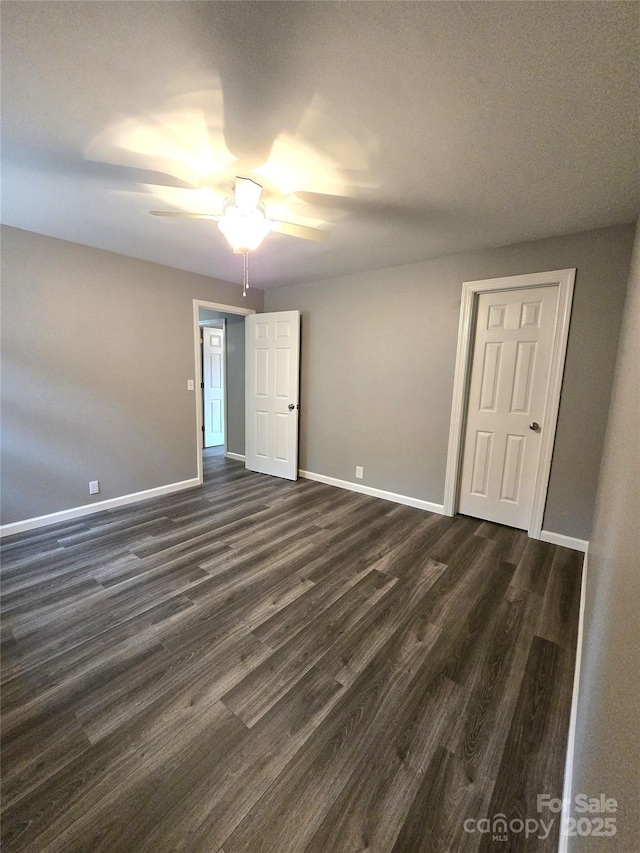 spare room featuring ceiling fan, dark wood-type flooring, and baseboards