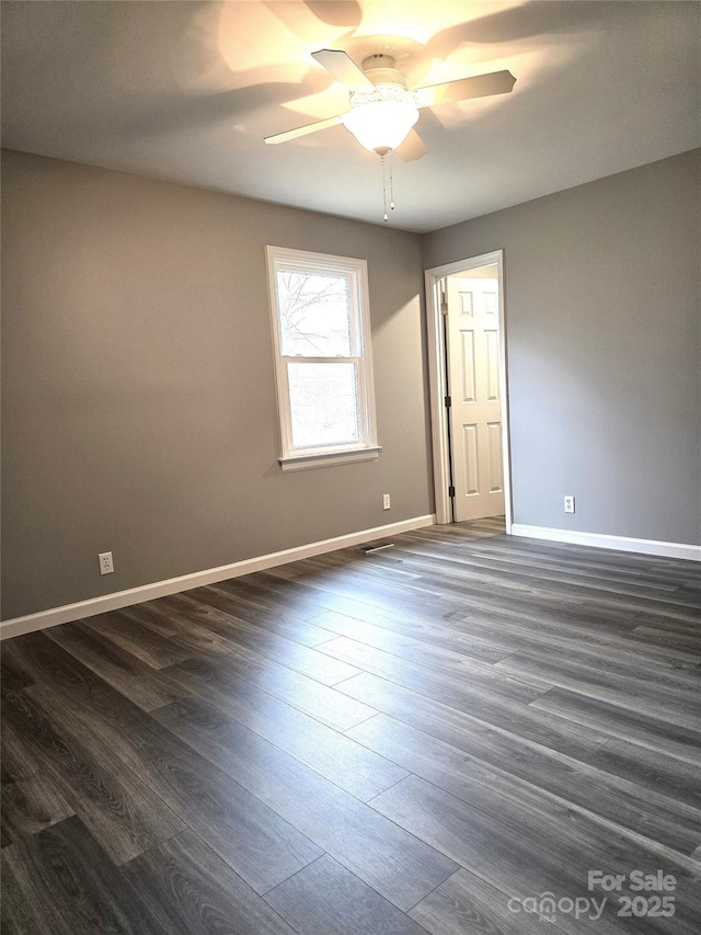 spare room featuring a ceiling fan, dark wood-style floors, and baseboards