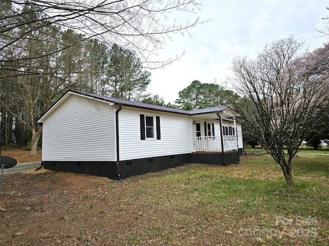 exterior space with crawl space, covered porch, metal roof, and a yard